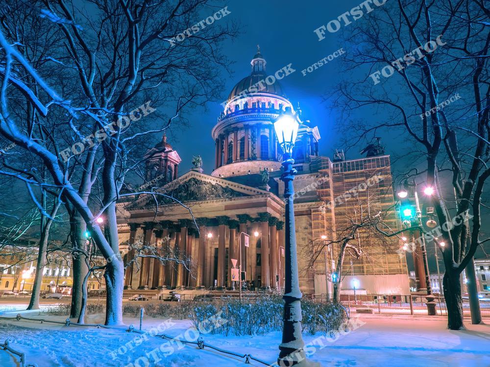 Зимняя праздничная атмосфера Санкт-Петербурга оживает на этом снимке: Исаакиевский собор сияет огнями в рождественскую ночь, а снежные улицы создают сказочный пейзаж. Идеальное фото для тех, кто ищет праздничный Петербург или планирует новогоднюю поездку в Россию. Красота архитектуры и зимнего города передана в деталях, делая изображение привлекательным для покупки и использования в туристических и праздничных проектах.